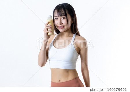笑顔でスムージーのペットボトルを持って体を鍛える女性 健康運動イメージ 筋トレ女子 トリミングアップ 笑顔でスムージーのペットボトルを持って体を鍛える女性 健康運動イメージ 筋トレ女子 トリミングアップ 140379491