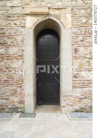 A dark wooden door is set within a stone archway A dark wooden door is set within a stone archway 140379727