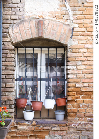 A window with bars is decorated with several hanging flower pots A window with bars is decorated with several hanging flower pots 140379822