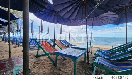 Blue Beach Umbrellas and Striped Deck Chairs on a Tropical Sandy Beach in Thailand 140380757