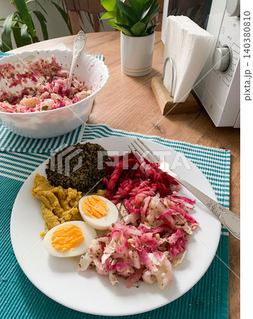 A nutritious breakfast featuring quinoa pancakes, fresh cabbage, radish, mung bean sprouts, boiled eggs, hummus, and roasted beets, perfect for a balanced start to your day 140380810