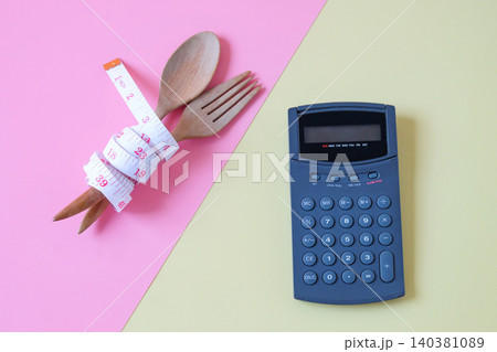 A tape measure wrapped in Wooden fork and spoon with calculator. A tape measure wrapped in Wooden fork and spoon with calculator. 140381089