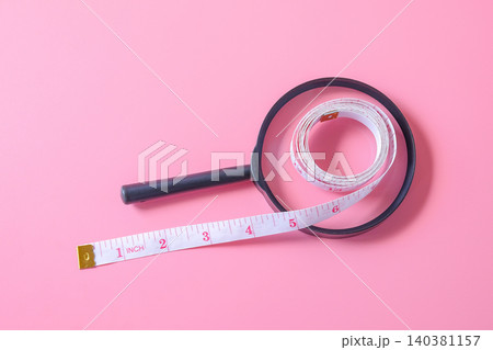 A magnifying glasson with measuring tape on background. A magnifying glasson with measuring tape on background. 140381157