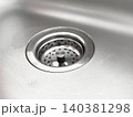Closeup view of drain with circular metal strainer with holes in kitchen sink for washing dishes. Sink surface appears smooth and shiny, details of metal. Details of interior 140381298