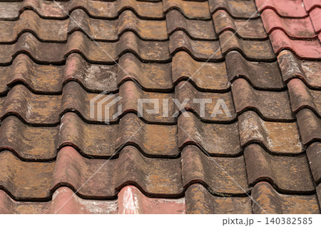 Roof tiles with varied colors on a building in sunlight Roof tiles with varied colors on a building in sunlight 140382585
