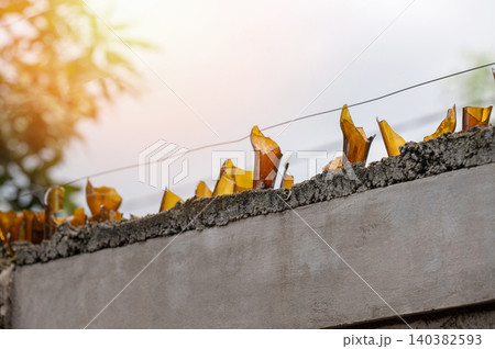 Broken glass used as fencing material on top of a concrete wall Broken glass used as fencing material on top of a concrete wall 140382593