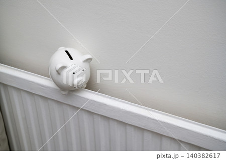 Piggy bank on home radiator, household energy savings heating costs and utility budget concept, copy space Piggy bank on home radiator, household energy savings heating costs and utility budget concept, copy space 140382617