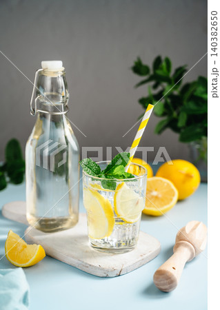 Lemon infused water with mint in glass beside bottle, healthy hydration and wellness concept, copy space Lemon infused water with mint in glass beside bottle, healthy hydration and wellness concept, copy space 140382650