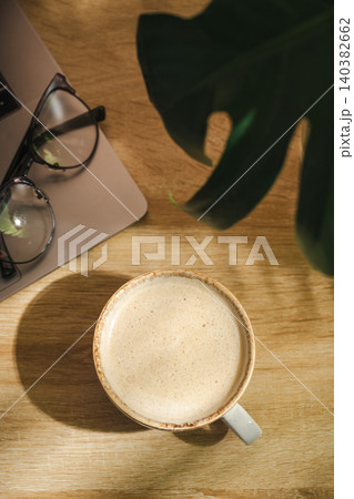 Coffee cup with plant shadow on wooden desk, morning lifestyle background with copy space 140382662