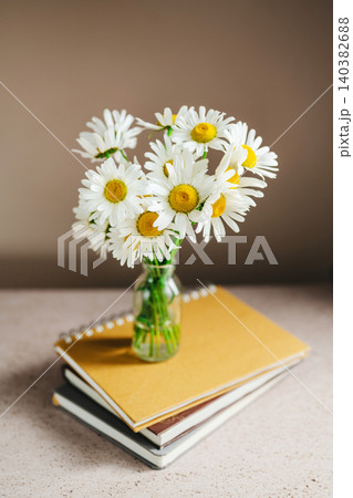 Daisy bouquet on stacked notebooks, study inspiration concept, copy space Daisy bouquet on stacked notebooks, study inspiration concept, copy space 140382688