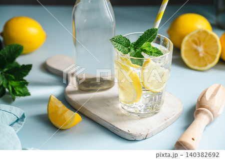 Lemon infused water with mint in glass beside bottle, healthy hydration and wellness concept, copy space Lemon infused water with mint in glass beside bottle, healthy hydration and wellness concept, copy space 140382692