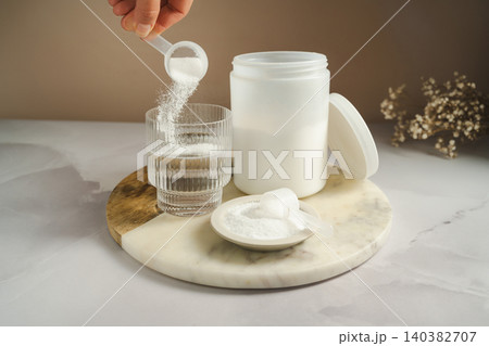 Collagen peptides supplement preparation with powder added to glass of water Collagen peptides supplement preparation with powder added to glass of water 140382707
