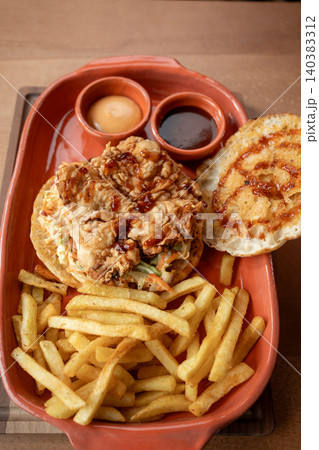 Delicious fried chicken sandwich with golden fries served in a rustic setting Delicious fried chicken sandwich with golden fries served in a rustic setting 140383312