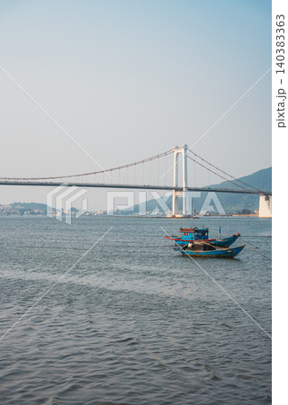 Fishing boats on Han river with Cau Thuan Phuoc bridge and city skyline at sunset in Da Nang, Traditional fisherman vessels on Golden Gate, calm water and mountains background, Danang Vietnam 4k 140383363