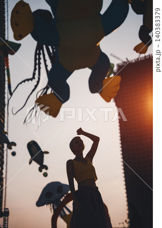 young woman walking on sand beach at colorful kite toys festival during summer sunset, girl enjoying freedom and joy at outdoor event by sea young woman walking on sand beach at colorful kite toys festival during summer sunset, girl enjoying freedom and joy at outdoor event by sea 140383379