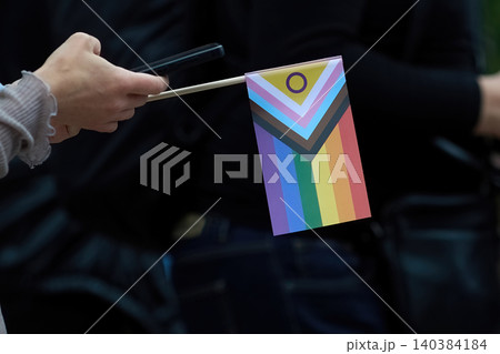 Hand holding intersex progress pride flag with smartphone Hand holding intersex progress pride flag with smartphone 140384184