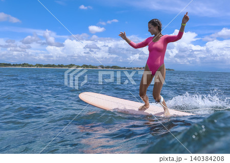 Cheerful Young Lady Balances On surfboard Amid Stormy Skies And Powerful Seas Cheerful Young Lady Balances On surfboard Amid Stormy Skies And Powerful Seas 140384208