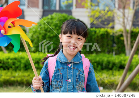 Happy Asian little girl walking in park with colorful pinwheel and backpack, cheerful child outdoor lifestyle, education and childhood concept Happy Asian little girl walking in park with colorful pinwheel and backpack, cheerful child outdoor lifestyle, education and childhood concept 140387249