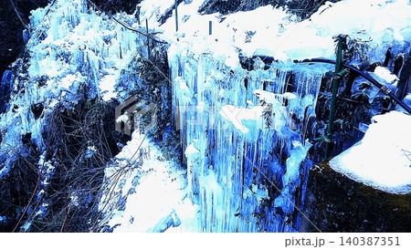 雪深い渓流沿いに、無数の氷柱が青く輝く幻想的な冬の風景。 雪深い渓流沿いに、無数の氷柱が青く輝く幻想的な冬の風景。 140387351