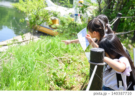 新緑の湖畔で地図を持ち遠くを指差すリュックを背負った女子小学生たち 新緑の湖畔で地図を持ち遠くを指差すリュックを背負った女子小学生たち 140387710