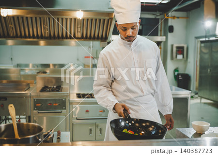Culinary student practicing wok cooking with vegetables during professional kitchen training Culinary student practicing wok cooking with vegetables during professional kitchen training 140387723