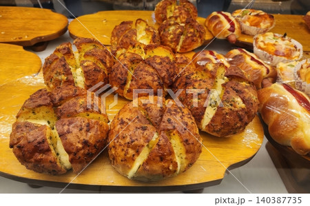 Freshly Baked Korean Cream Cheese Garlic Bread on a Wooden Display Tray in a Bakery Freshly Baked Korean Cream Cheese Garlic Bread on a Wooden Display Tray in a Bakery 140387735