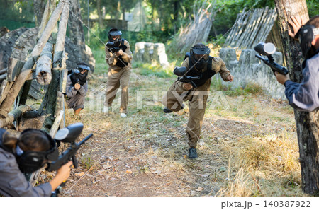 Group of friends paintball players of opposite teams in shootout in forest Group of friends paintball players of opposite teams in shootout in forest 140387922