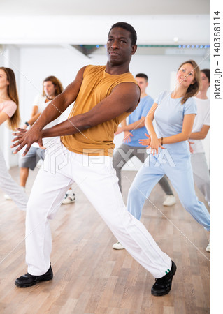 Happy multiracial men women of different ages performing dynamic energetic dancing movements in modern loft studio Happy multiracial men women of different ages performing dynamic energetic dancing movements in modern loft studio 140388114