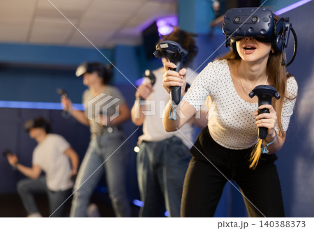 girl in virtual reality helmet crouches down and dodges flying asteroids during space adventure game 140388373