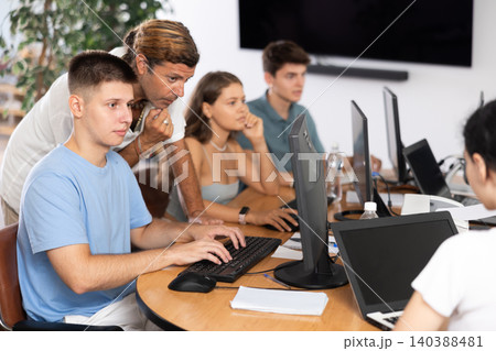 Interested guy attending computer class under guidance of male teacher Interested guy attending computer class under guidance of male teacher 140388481