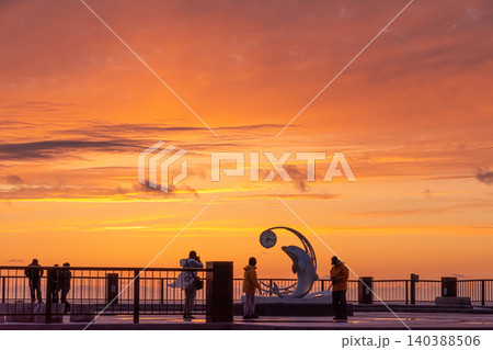 美しい夕焼け空と海岸沿いの広場に佇む人々のシルエット 美しい夕焼け空と海岸沿いの広場に佇む人々のシルエット 140388506