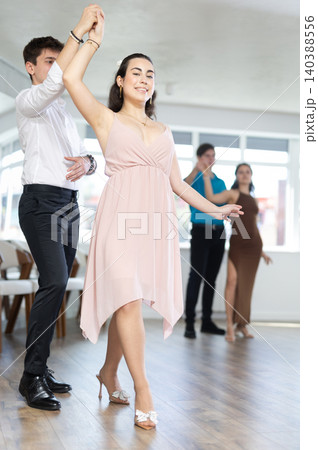 Hispanic guy enjoying merengue with young female partner in dance class Hispanic guy enjoying merengue with young female partner in dance class 140388556