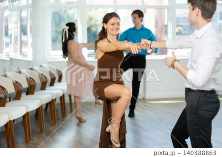 Couple in evening dresses enjoys pair dance boogie-woogie, interacting with each other on floor Couple in evening dresses enjoys pair dance boogie-woogie, interacting with each other on floor 140388863