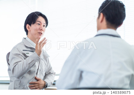 医師の診察を受ける作業着の男性 産業医の面談 健康診断 腹痛 頭痛 相談 医師の診察を受ける作業着の男性 産業医の面談 健康診断 腹痛 頭痛 相談 140389075