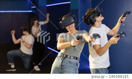 Portrait of woman using virtual reality goggles controlling joysticks standing in dark room 140389185