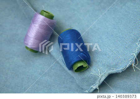 Colorful Thread Spools on Blue Denim Fabric Colorful Thread Spools on Blue Denim Fabric 140389373