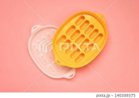 Yellow and White Silicone Sausage Molds on Pink Background Yellow and White Silicone Sausage Molds on Pink Background 140389375