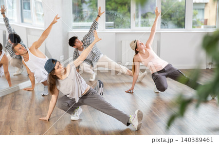 Girl and her students perform hip hop dance on one bent leg, movement in horizontal plane near floor 140389461