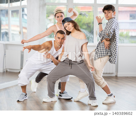 Active girls and guys demonstrating breakdance poses in training hall 140389602