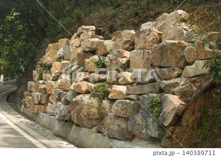 Stone retaining wall along a winding road in a natural setting Stone retaining wall along a winding road in a natural setting 140389711