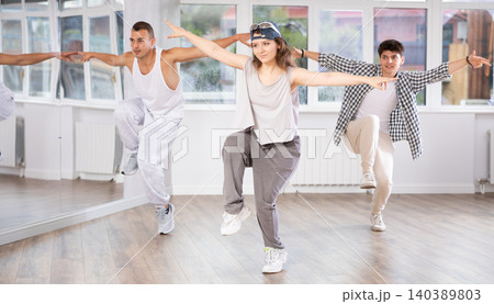 Active men and girls practicing hip-hop dance in training hall during group dancing classes Active men and girls practicing hip-hop dance in training hall during group dancing classes 140389803