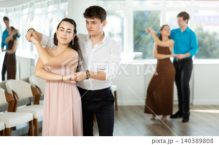 Hispanic guy practicing bachata with young brunette in dance class Hispanic guy practicing bachata with young brunette in dance class 140389808