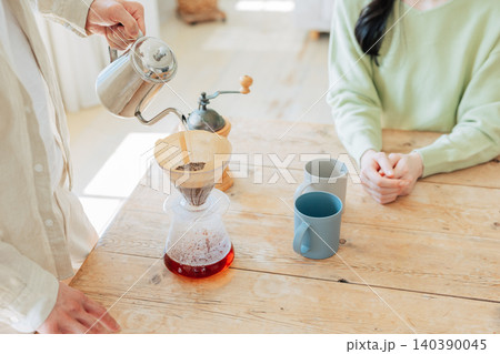 コーヒーを淹れる男性の手元と待っている女性 コーヒーを淹れる男性の手元と待っている女性 140390045