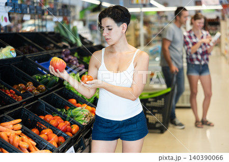 Woman choosing tomatoes in supermarket Woman choosing tomatoes in supermarket 140390066