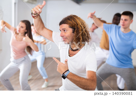 Group of excited young adult diverse dancers performing dynamic movements during training together in fitness studio Group of excited young adult diverse dancers performing dynamic movements during training together in fitness studio 140390081