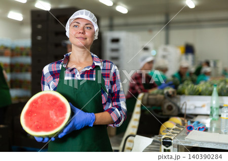 Female agricultural facility worker holding half of fresh watermelon Female agricultural facility worker holding half of fresh watermelon 140390284