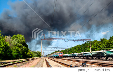Trains moving along the railway tracks near Brovary train station under a large plume of black smoke from an explosion near Kyiv in Ukraine. Trains moving along the railway tracks near Brovary train station under a large plume of black smoke from an explosion near Kyiv in Ukraine. 140391169