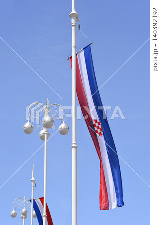Vertical flag of Croatia hanging from a white flagpole against blue sky Vertical flag of Croatia hanging from a white flagpole against blue sky 140392192