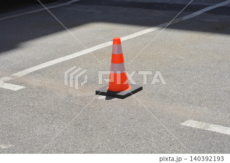 Orange traffic cone with reflective stripes on an asphalt parking space Orange traffic cone with reflective stripes on an asphalt parking space 140392193