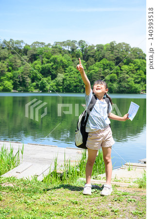 新緑の湖畔でしおりを持ち元気に手を挙げる遠足の女子小学生 新緑の湖畔でしおりを持ち元気に手を挙げる遠足の女子小学生 140393518